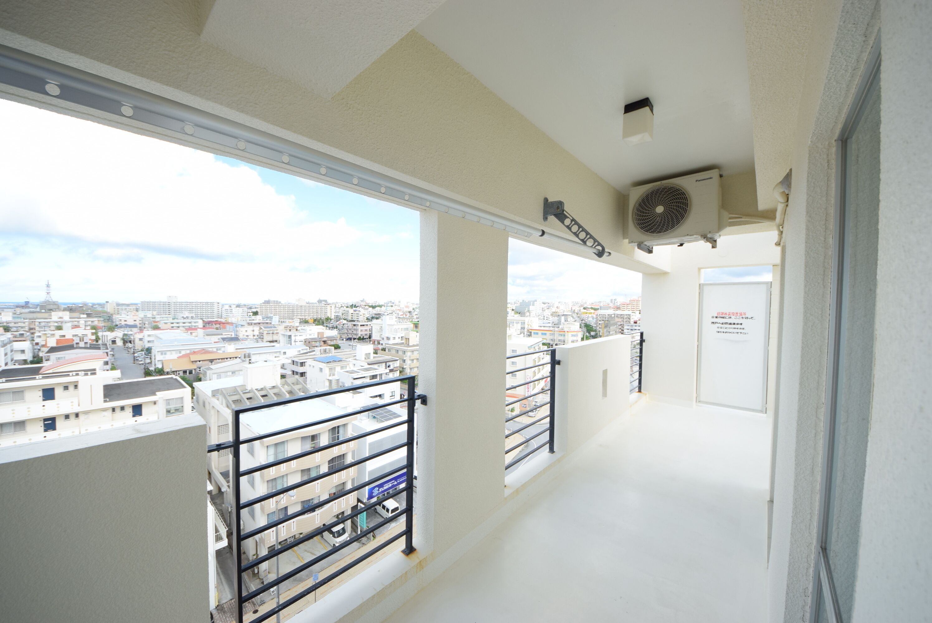 A balcony with a city view, a ceiling fan, and a door.