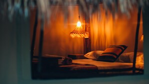 A room with a thatched roof, a bed with pillows, and a hanging light fixture. - Glamp Ikal Tulum (Tulum)