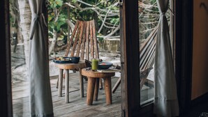 A wooden deck with two wooden chairs and a small table, each with a bowl and a cup. - Glamp Ikal Tulum (Tulum)