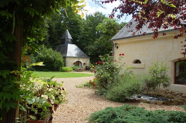 Un jardin agrémenté d’un bâtiment en pierre, d’un petit étang et de diverses plantes.