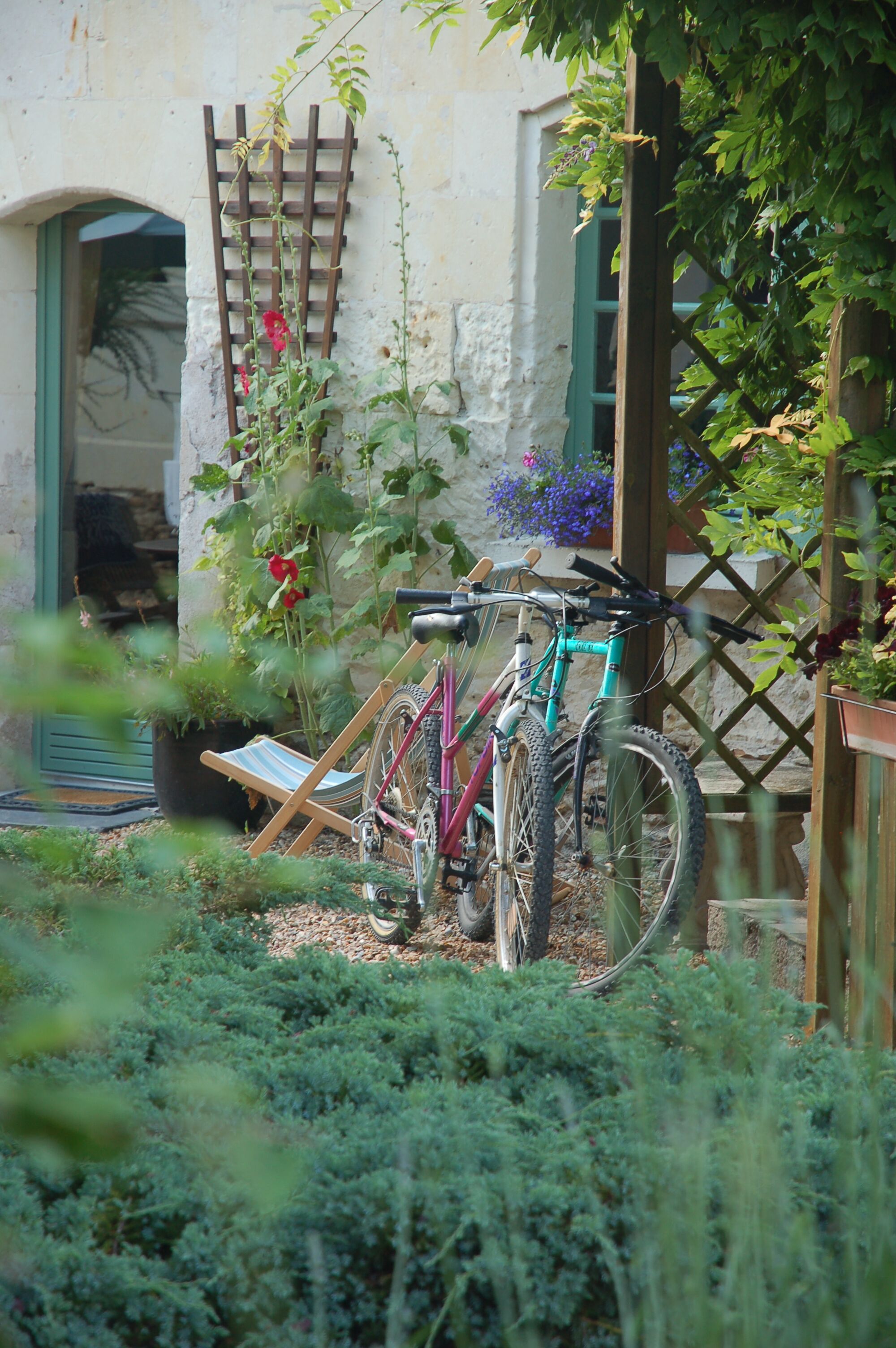 Ein Fahrrad, das an einem Holzzapfen in einem Garten mit Topfpflanzen und einer Tür lehnt.