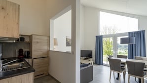 Eine moderne Küche mit Essbereich, großen Fenstern und Blick auf Grünflächen.