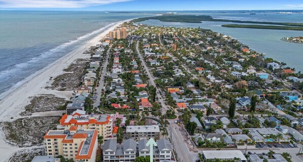 An aerial view of Sugar Sand Sanctuary with beachfront properties, a central road, and a swimming pool area.
