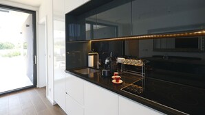 A modern kitchen with a black countertop, stainless steel appliances, and a coffee machine. - Villa Lana - Home4You (Kraj)