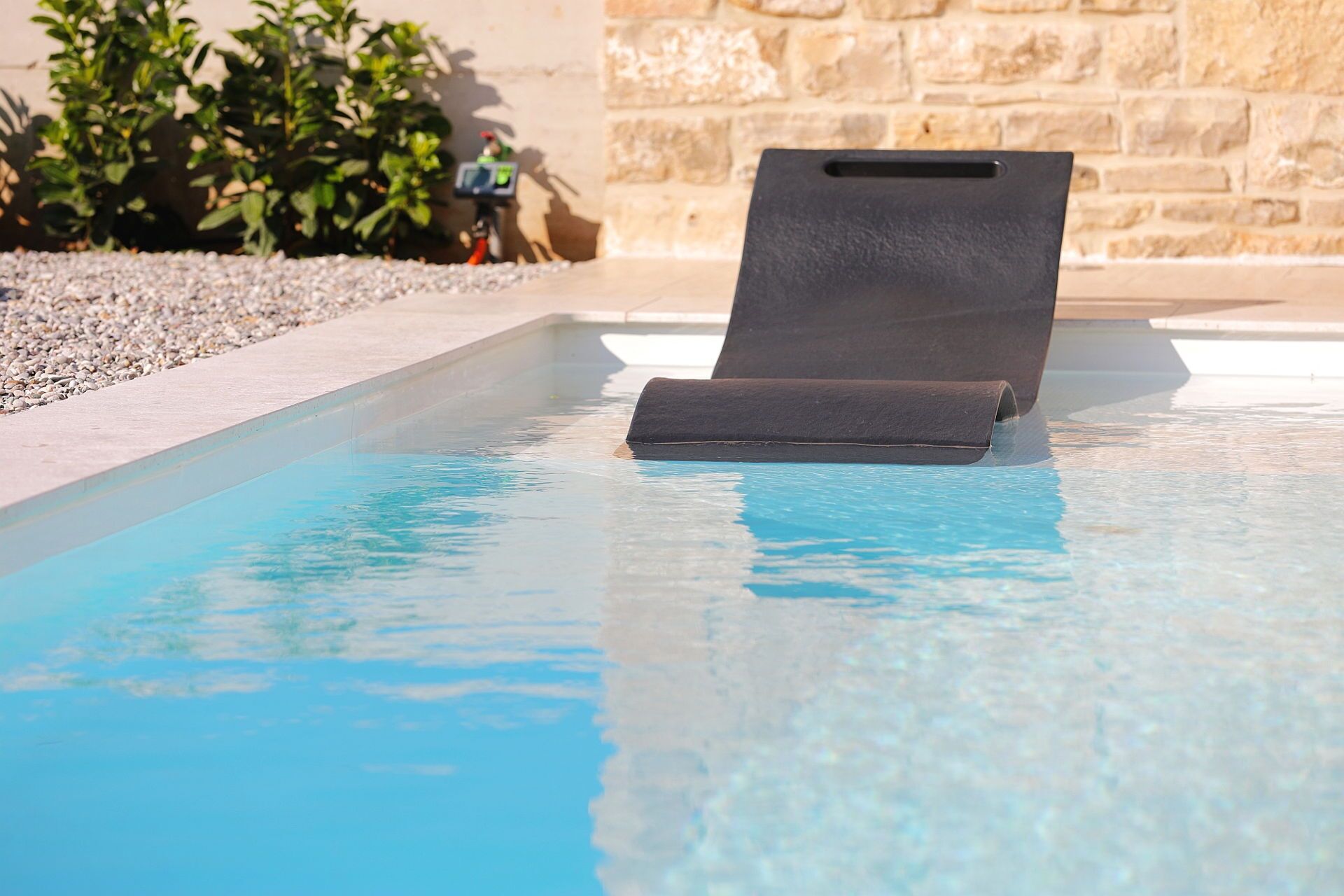 A pool with a black lounge chair.