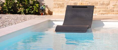 A pool with a black lounge chair.