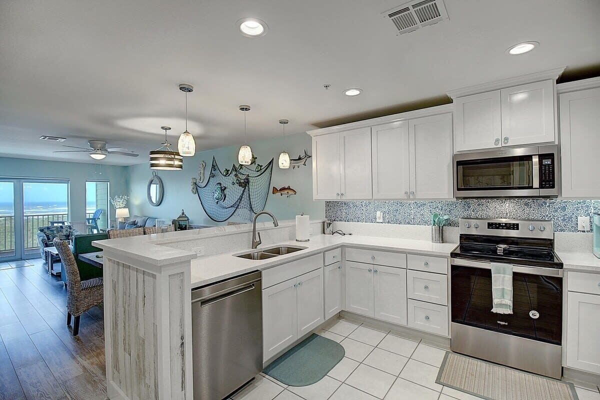A modern kitchen with white cabinetry, stainless steel appliances, and a large island.