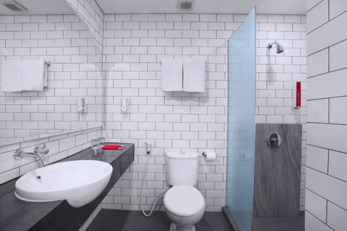 Ein modernes Badezimmer mit weißen Fliesen, einem weißen Waschbecken, einer Toilette und einer Duschkabine.