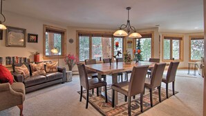 A spacious dining area with a large wooden table and multiple chairs, surrounded by large windows offering views of the outdoors.