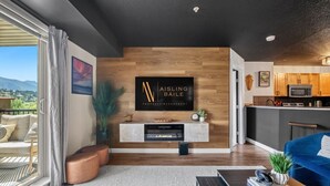 Una sala de estar moderna con un televisor de pantalla plana, paneles de madera en la pared, una chimenea y vistas al exterior.
