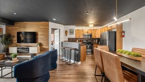 Una cocina moderna con una isla central, armarios de madera, electrodomésticos de acero inoxidable y un comedor con asientos de cuero.