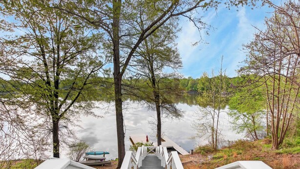 A wooden staircase leading to a dock by a calm lake, surrounded by trees. - Lake Anna Waterfront - Sleeps 21 - Dock for 3 Boats (Orange)