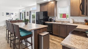 A modern kitchen with dark wood cabinets, a granite countertop, and a dining area with wicker chairs. - Lake Anna Waterfront - Sleeps 21 - Dock for 3 Boats (Orange)