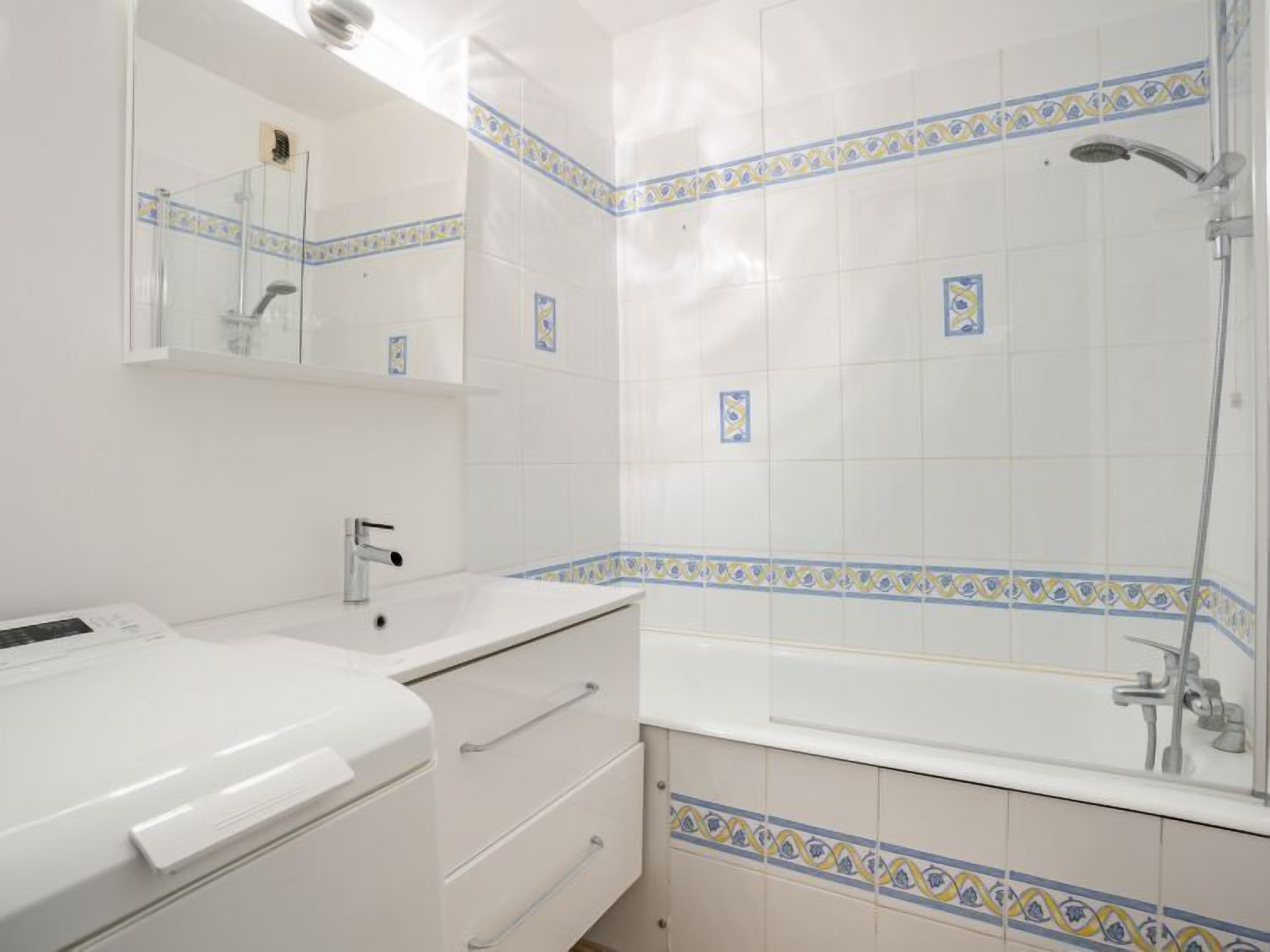 A bathroom with a white sink, mirror, and bathtub.