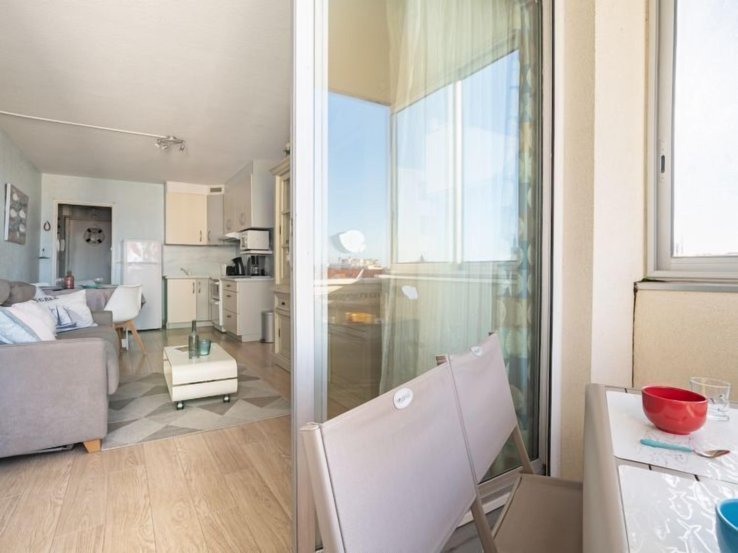 A modern apartment with a living room, kitchen, and balcony.