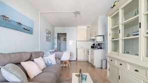 A modern living room with a sofa, coffee table, and a kitchen area with cabinets and a microwave. - Port Arcachon by Interhome (Arcachon)