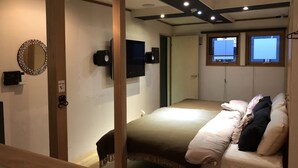 A bedroom with a bed, a TV, a mirror, and a window.