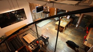 A spacious living area with a high ceiling, a dining table, and a sofa.