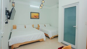 Habitación de hotel con dos camas, un televisor de pared, un cuadro y un ventanal corredero.