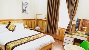 A hotel room with a wooden bed, a desk, a chair, and a small table.