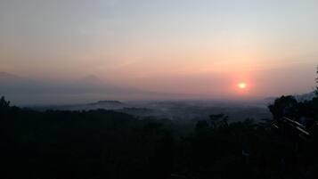 A sunrise over a mountainous landscape with a view of the sun rising over the horizon.