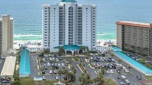 A high-rise hotel with a central courtyard, parking lot, and ocean view.