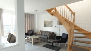 Una sala de estar moderna con un sofá gris, una mesa de centro y una escalera de madera.