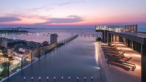 A rooftop pool with a view of the city and the sea at dusk. - Pony's Homestay -The Base Condo- (Bang Lamung)