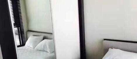 A hotel room with a large bed, a headboard, and a mirror reflecting the room.