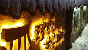 Un muro de piedra con letras iluminadas que dicen "Hotel" y "Estación de Esquí".
