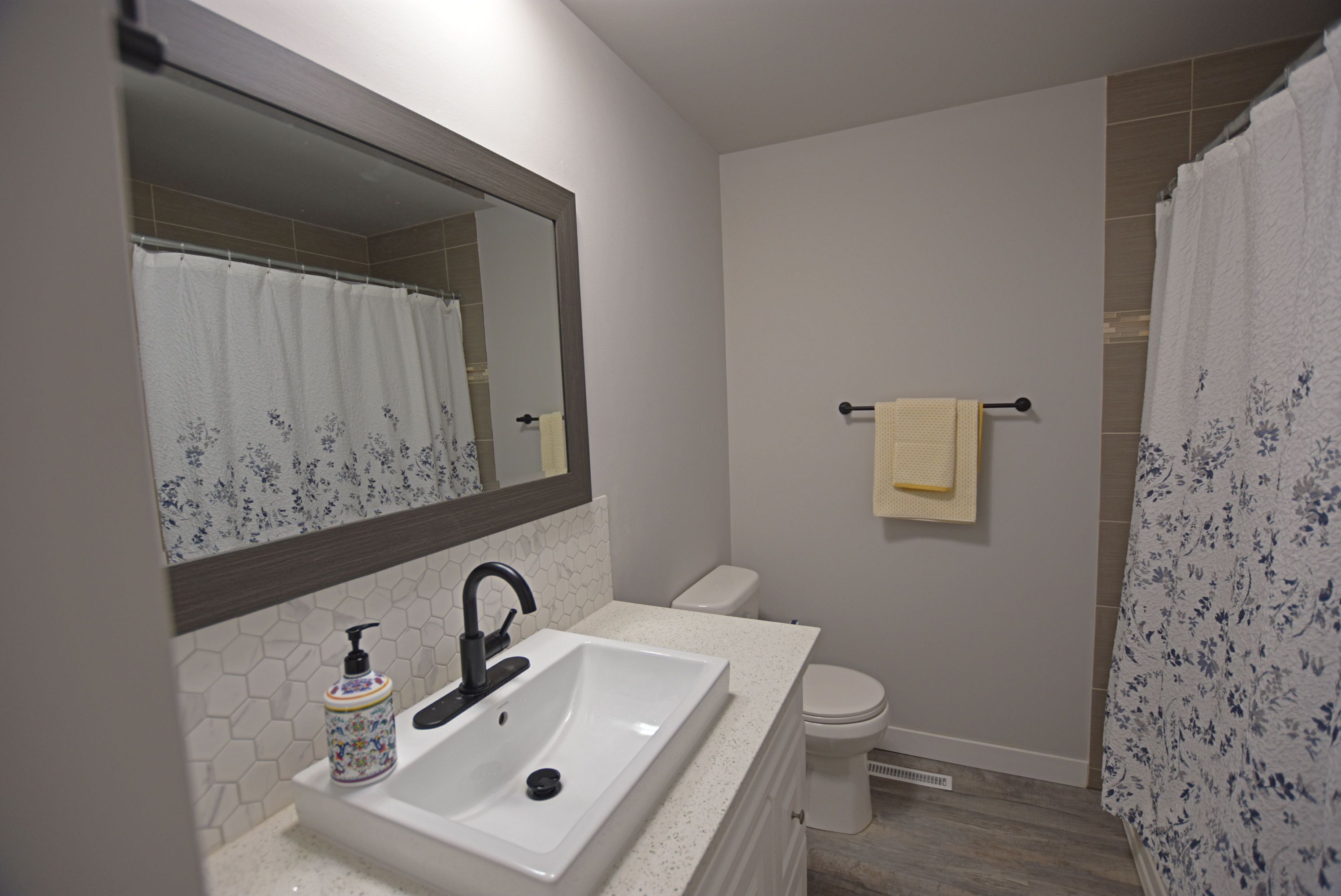A bathroom with a white sink, a mirror, a toilet, and a shower curtain.