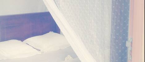 A bed with a white canopy and a blue patterned curtain.