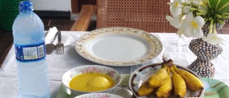 Uma mesa de jantar com pratos, tigelas, uma garrafa e uma cadeira.