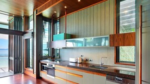 Una cocina moderna con una isla grande, electrodomésticos integrados y amplios ventanales que ofrecen vistas al exterior.