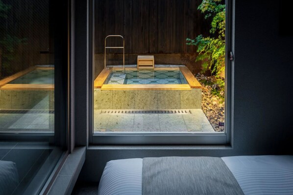 A modern room with a large window overlooking a small outdoor hot tub area.