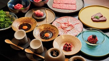 Una variedad de platos sobre una mesa, con carne cruda, verduras y salsas.