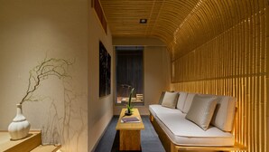 Ein modernes Interieur mit einer Holzbank, einem weißen Sofa und einem kleinen Tisch mit Pflanze und Buch.