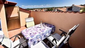 Een balkon met een tafel en stoelen, een houten deur en uitzicht op een stad.