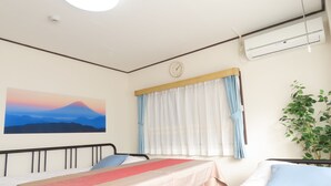 Une chambre d’hôtel avec deux lits, un tableau représentant une montagne, une horloge et un appareil de climatisation.