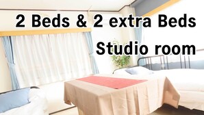 Une chambre dotée de deux lits et de deux lits d’appoint, classée comme studio.