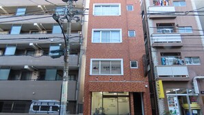 Un immeuble à plusieurs étages, doté d’une façade en briques, de nombreux balcons et d’une entrée au niveau du sol avec une porte en verre.
