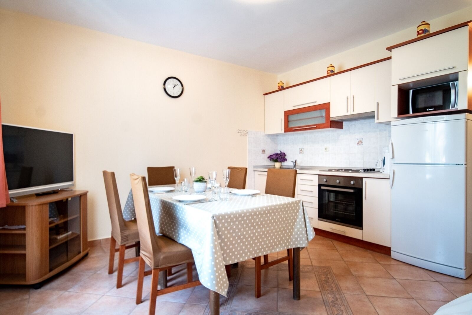 A compact kitchen with white cabinets, a microwave, oven, and a dining area with a table set for four.