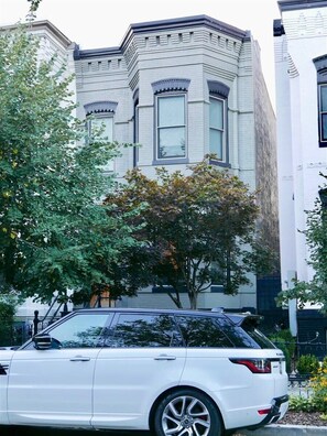 A white car parked in front of a building with a large tree in the foreground. - Slumber in Sophistication in Shaw-PKG (Washington)