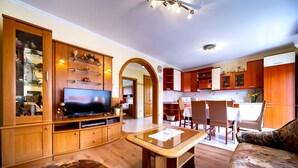 A modern living room with a flat-screen TV, wooden cabinets, a glass coffee table, and a patterned sofa. - Apartment in Lopar with Balcony, Air condition, WIFI, Washing machine (4886-2) (Lopar)