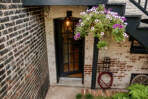 A brick building with a black door, a hanging flower basket, and a red hose on the ground. - Amazing Location - Close to Union Station (Washington)