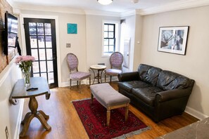 A living room with a leather sofa, two patterned chairs, a small round table, a red rug, and a vase with flowers. - Amazing Location - Close to Union Station (Washington)