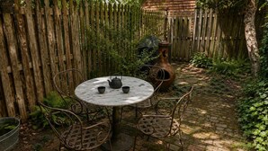 A round metal table with chairs, a metal pot, and a teapot on a brick patio. - Amazing Location - Close to Union Station (Washington)