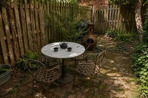 A round metal table with chairs, a metal pot, and a teapot on a brick patio. - Amazing Location - Close to Union Station (Washington)