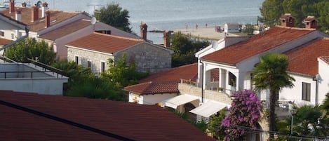 A coastal town with terracotta-roofed buildings, a marina, and a view of the sea.
