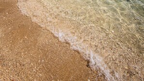 Une plage propre, avec une eau peu profonde et un rivage rocheux.